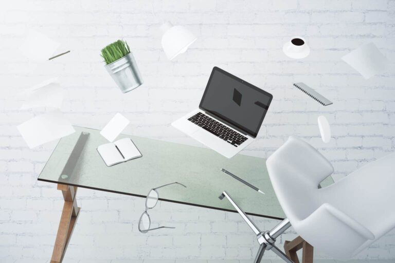 Desk with files, notes and technology flying through the air - a symbol of overload in the everyday life of an executive assistant.