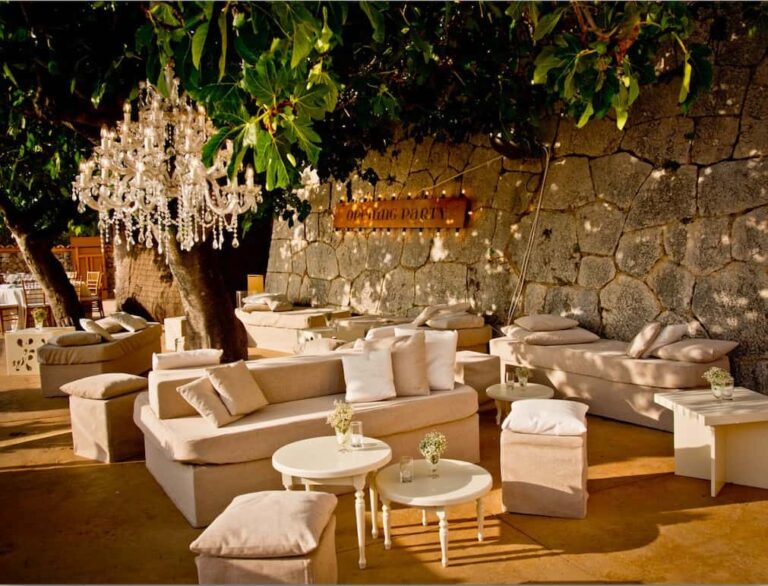 Mediterranean decoration with exclusive lounge furniture in front of a Mallorcan stone wall to present the stylish atmosphere for events on Mallorca.