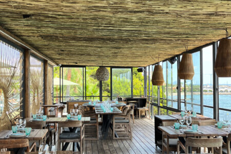 Boho-inspired beach restaurant with wooden tables, turquoise seating and sea views