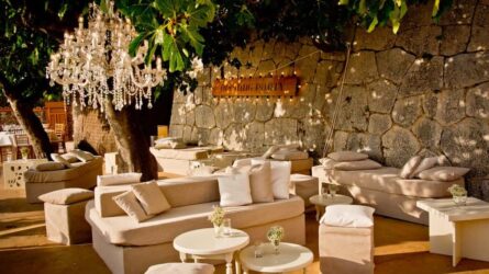 bm-concierge-eventmanagement Decoración mediterránea con mobiliario de salón exclusivo frente a una pared de piedra mallorquina para presentar un ambiente elegante para eventos en Mallorca.