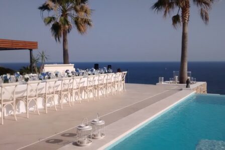 Elegant, festively laid table in a luxury villa in Mallorca with a view of the pool and the open sea