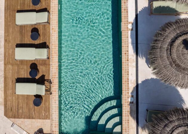 Aerial view of the designer pool area of the luxury finca The Hide Mallorca with wooden deck, sun loungers and parasols.