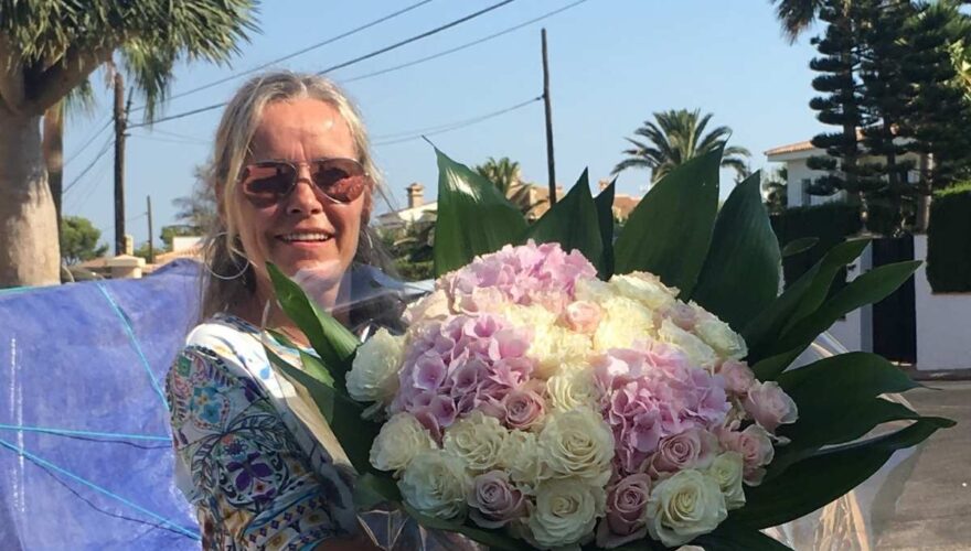 überraschungsgeschenk-bm-concierge-mallorca-düsseldorf bettina müller übergibt einen riesengroßen weiß-rosa-farbenen blumenstrauss als geburtstagüberraschung als geschenk eines kunden