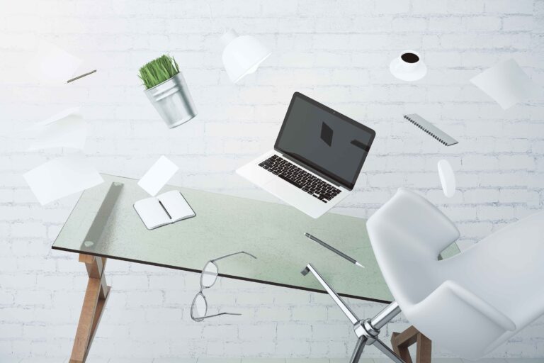 Moderner Schreibtisch mit schwebendem Laptop, Papieren und Accessoires – Symbol für kreative Dynamik und Organisation