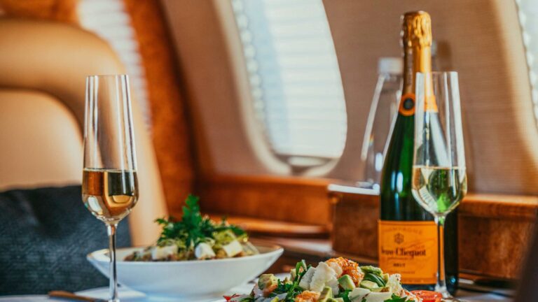 Stilvoll gedeckter Tisch mit Feinkost und einer Flasche Champagner im Privatjet